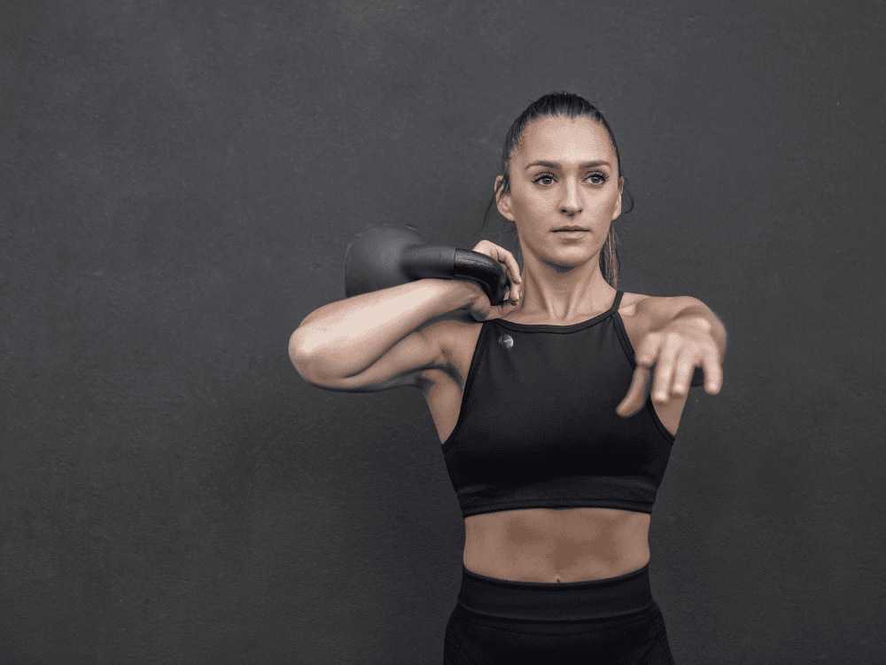 A woman using a wireless microphone for her kettlebell exercises vlog