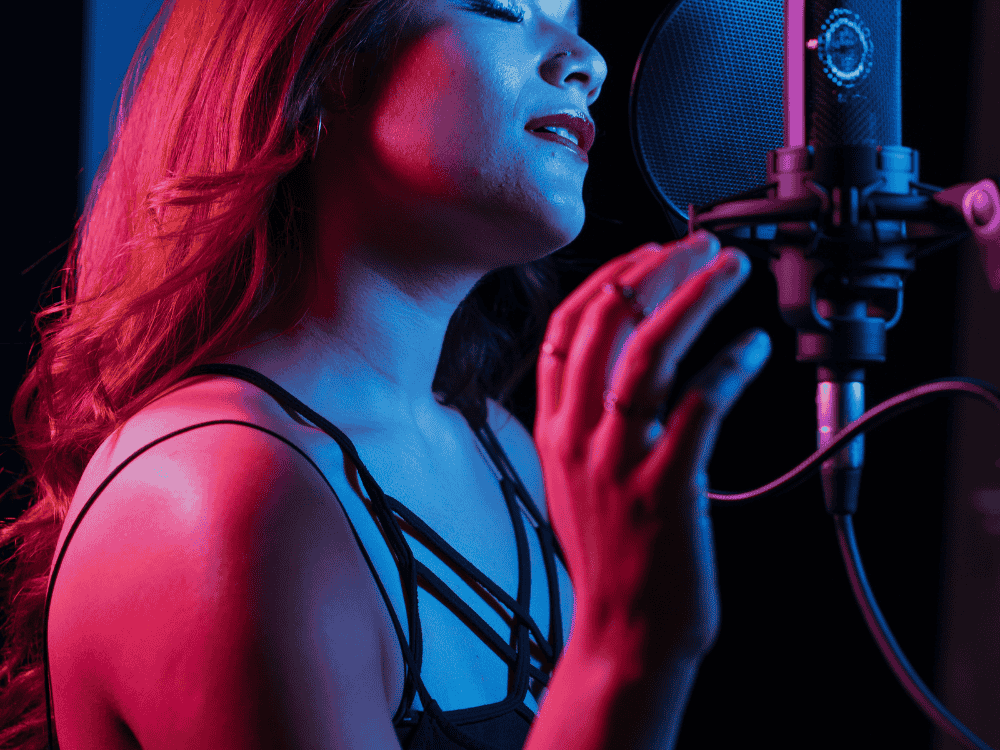 A woman recording at a home studio using a USB microphone for singing