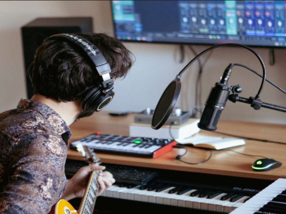 male home recording music with microphone and instruments