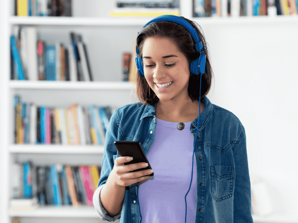 A female podcaster using a smartphone and a wireless microphone for recording her podcast