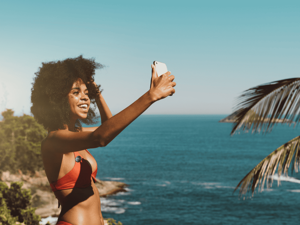 A woman vlogging on the beach with a smartphone and a wireless microphone