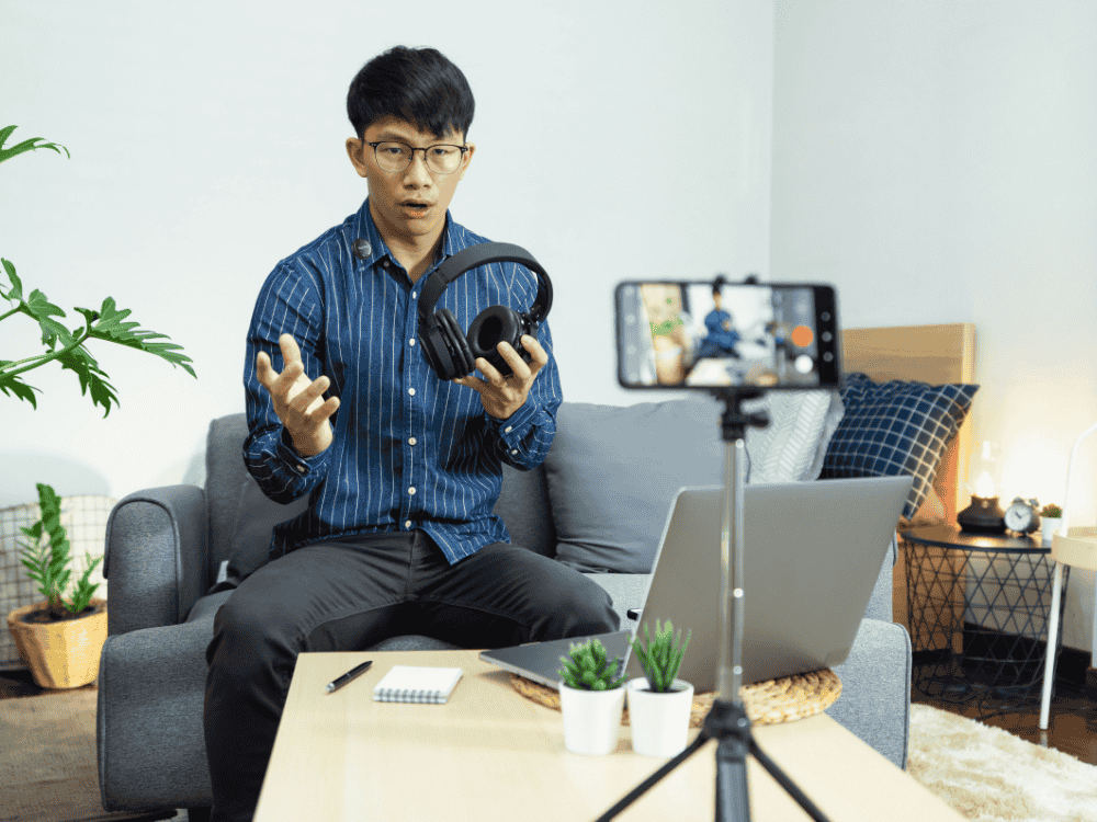 A tech vlogger using a wireless microphone for recording his headphone review vlog